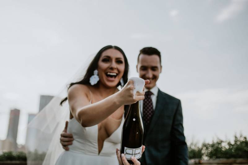 Bride smiling while foaming champagne drips' from hand  