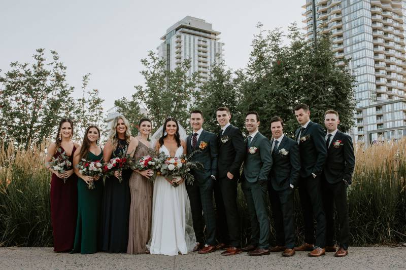 Bride and groom and bridesmaids and groomsmen stand in line on pathway
