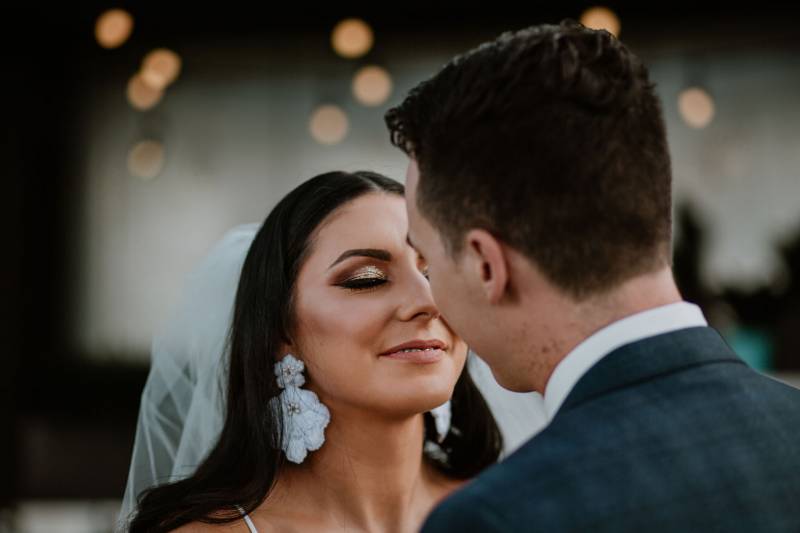 Bride and groom staring intently in white veil and large white earrings
