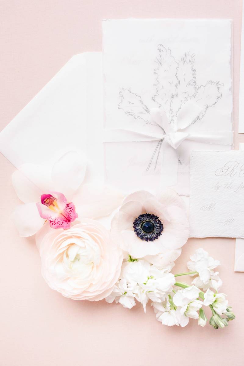 Blush letter flat lay with white and blush floral accents 