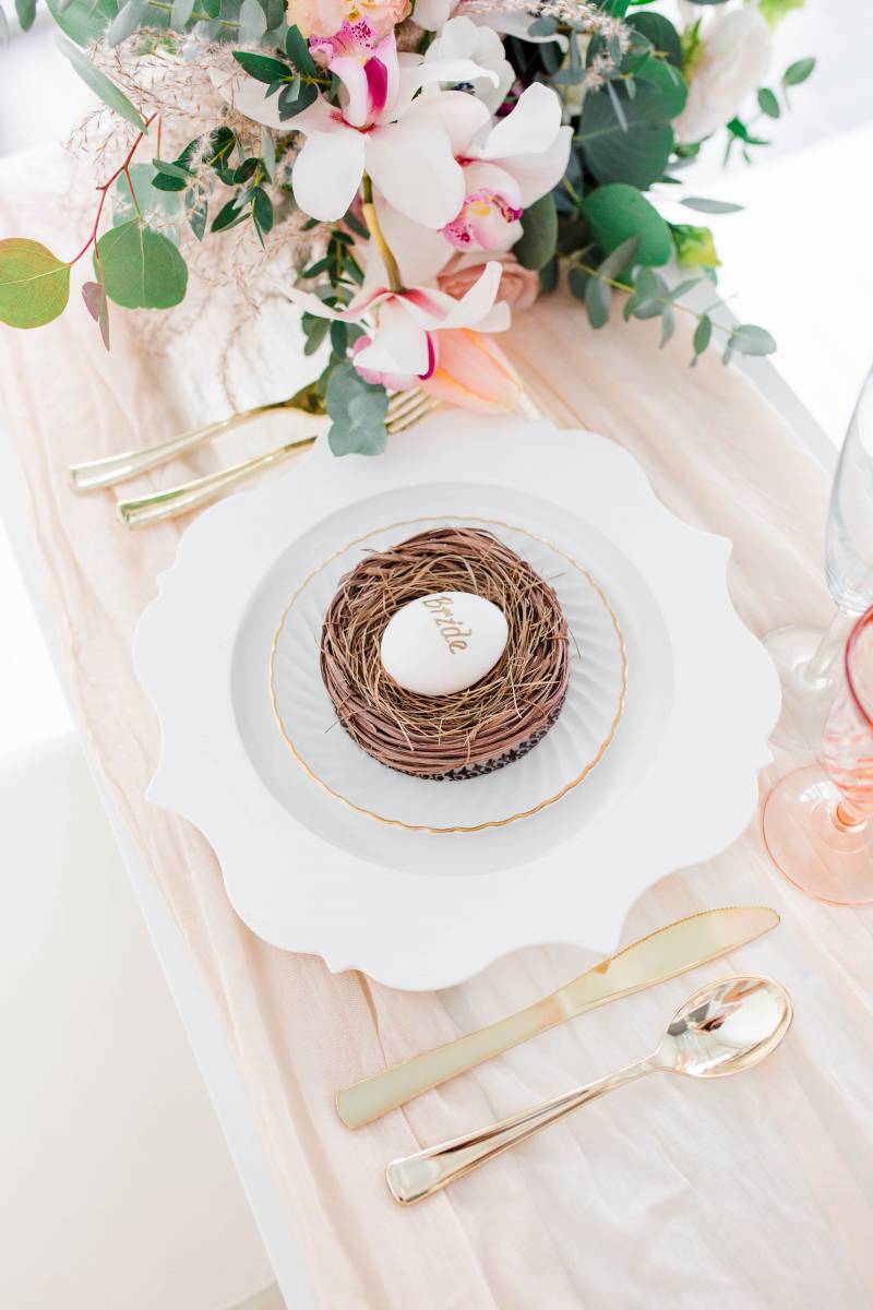 Table setting flat lay with gold cutlery and blush and white floral arrangement 