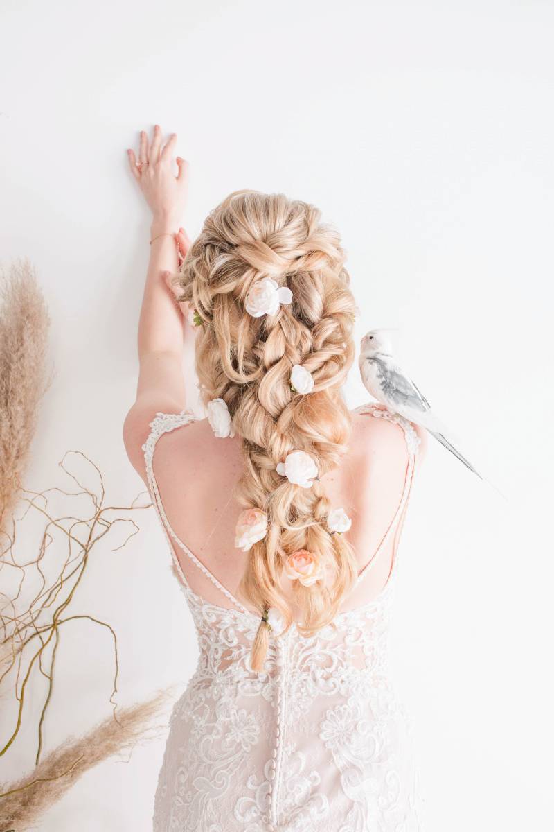 Bride facing wall in white lace open back dress with white cockatoo on shoulder 