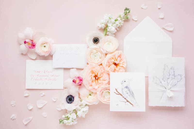 Blush letter flat lay with white and blush floral accents 