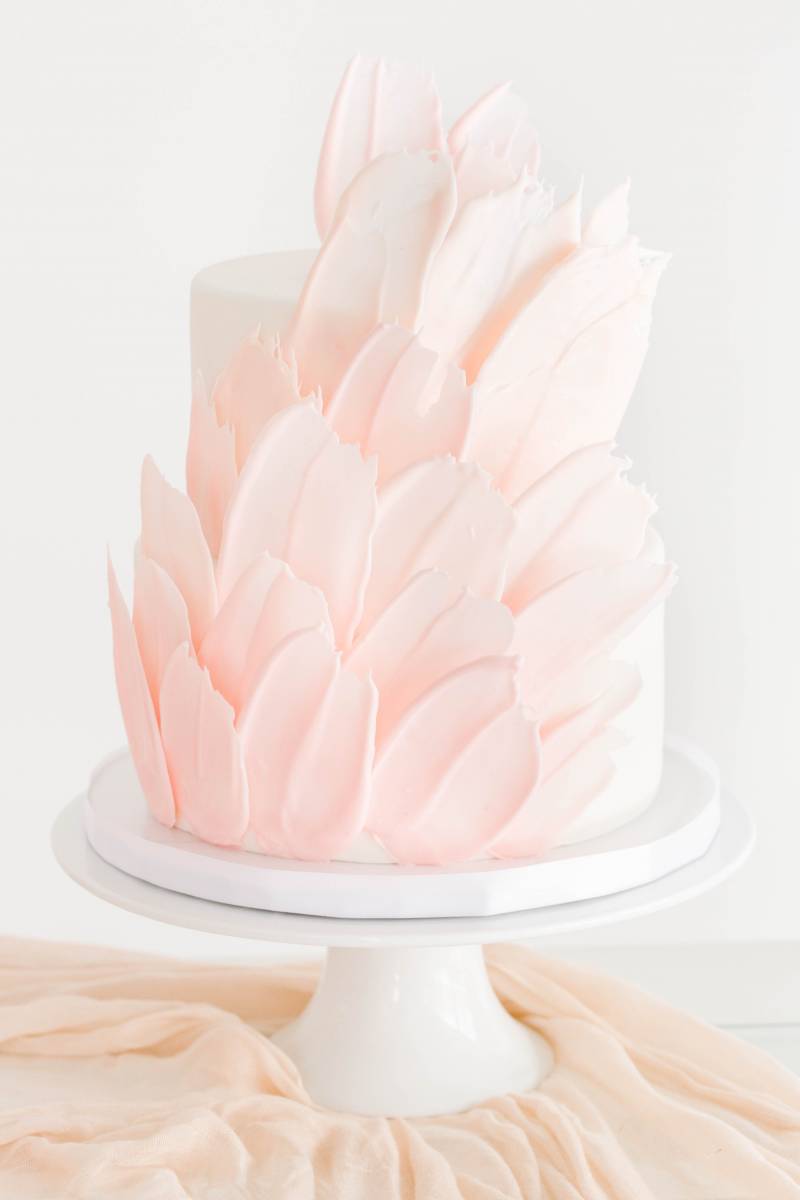 Pale pink floral wedding cake on blush silk table runner