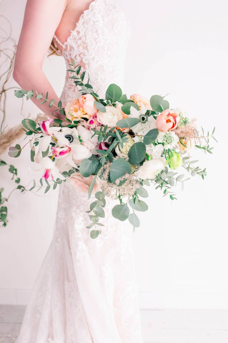 Blush pink white and yellow bouquet held by bride in white lace dress 