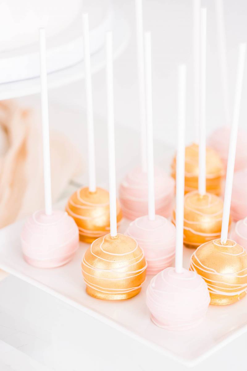 pale pink and gold cake pops on white table
