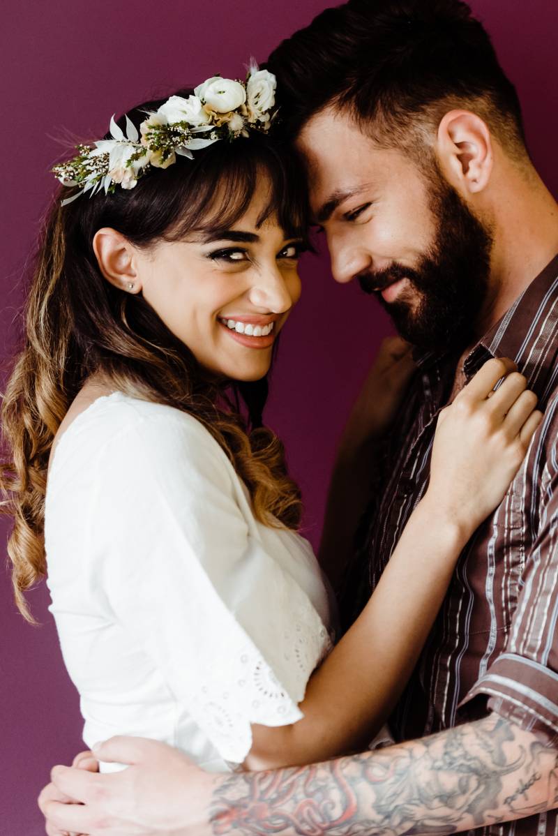 Man and woman embrace touching foreheads as woman smiles to side 