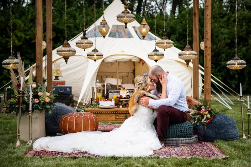 Man and woman embrace sitting on carpet and pouf under chandelier touching foreheads
