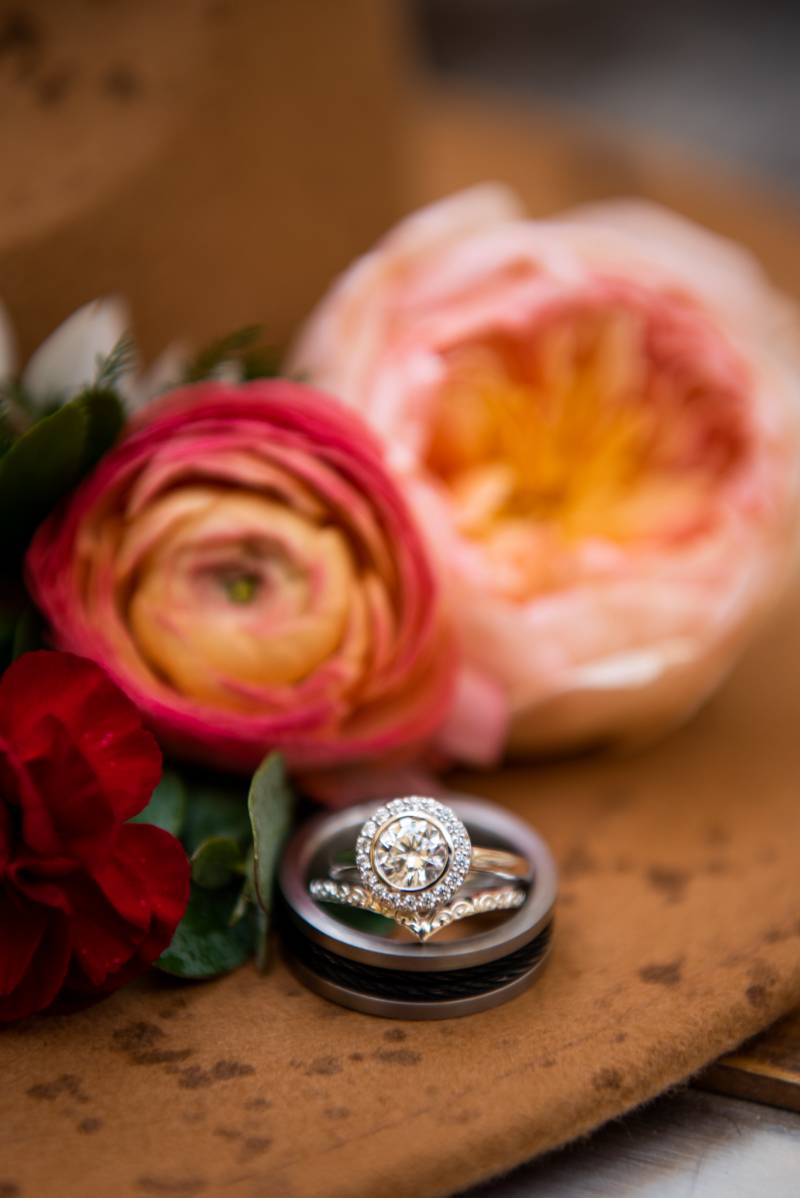 Engagement rings stacked in front of pink and orange flowers