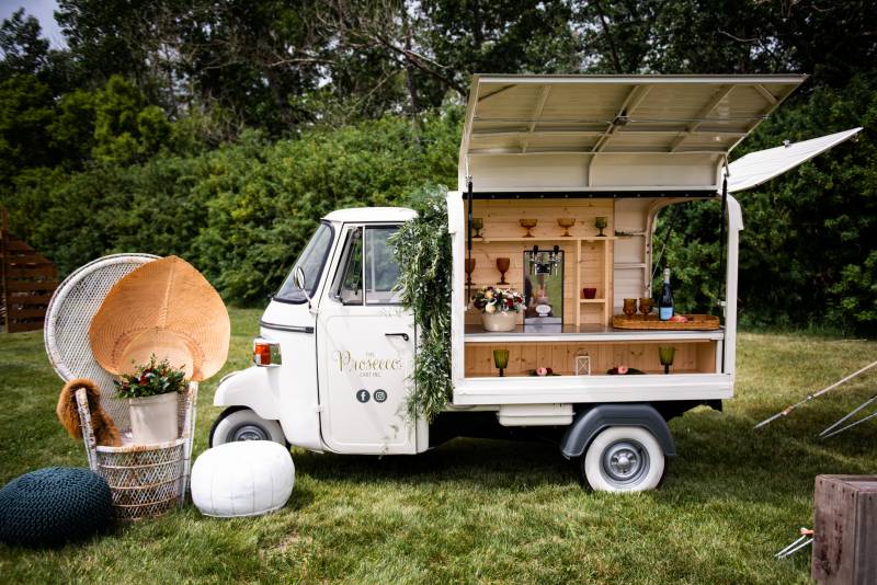 Food truck in grass field with wooden interior beside poufs and wicker seats 