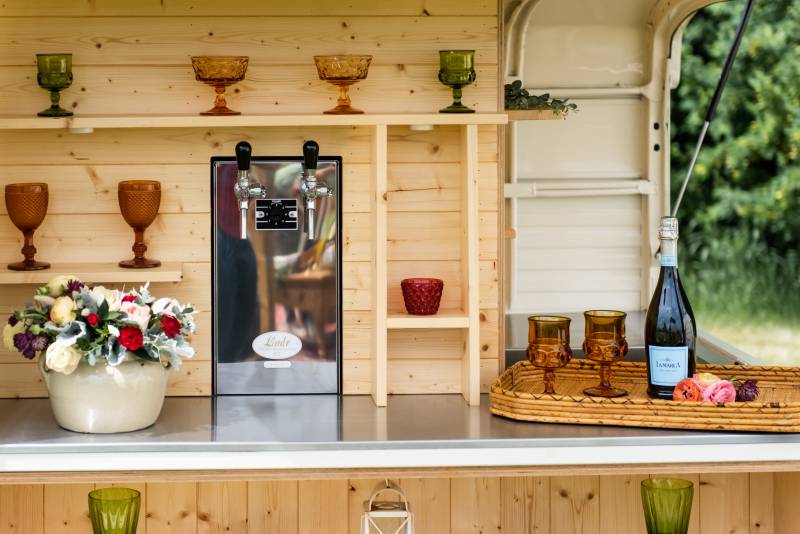 Food truck wooden interior with multicoloured glasses on shelves and bottle of champaign 