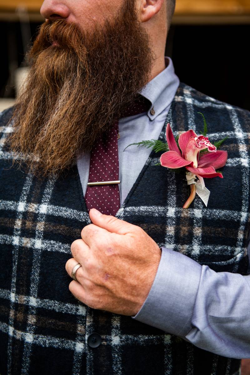 Man with large beard and plaid vest with pink boutonniere 