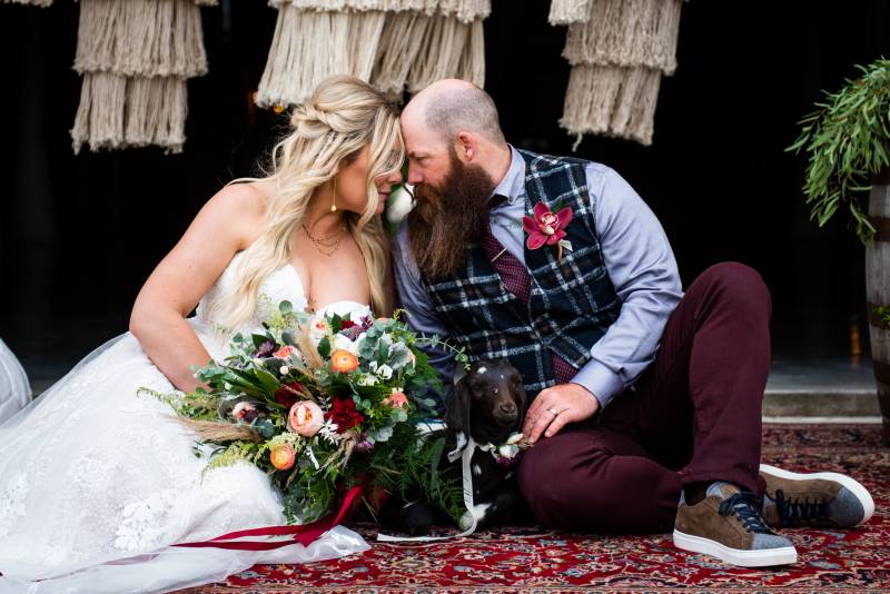 Man and woman sit touching foreheads holding bouquet on red shag carpet