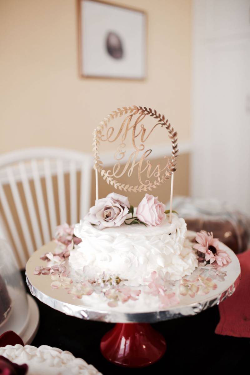 White wedding cake with blush floral accents on silver platter