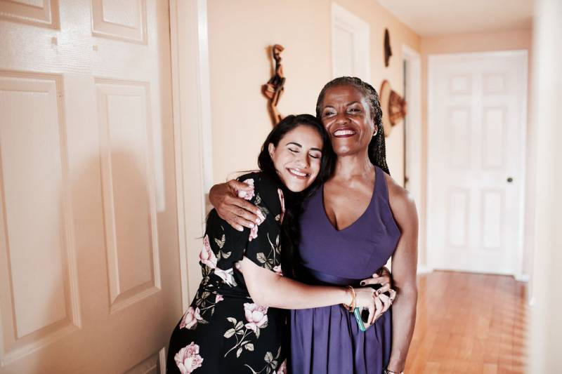 Two women embracing while smiling in hallway