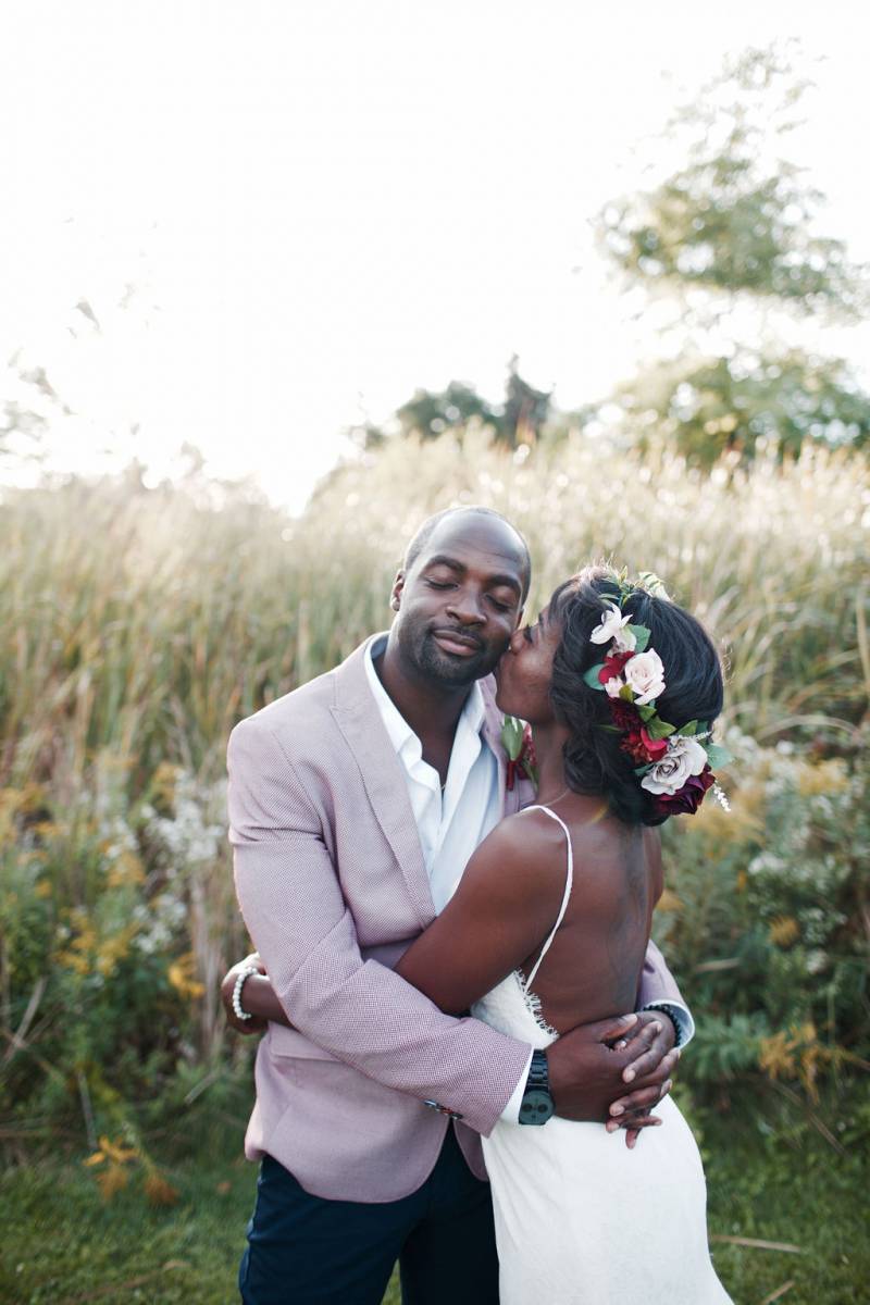 Bride and groom eyes closed embracing in grassy field