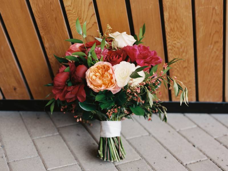 Large red peach and white bouquet leaning against wall 