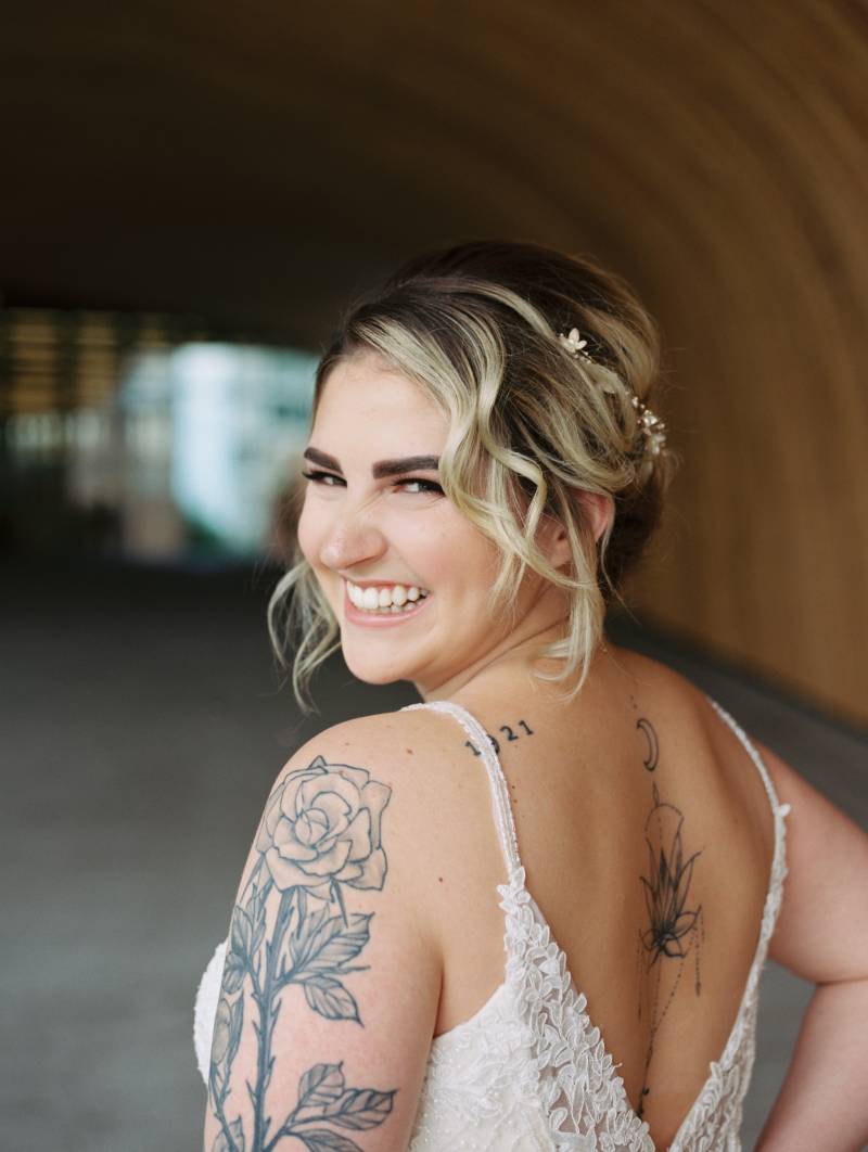 Bride smiling over shoulder in white lace open back dress 
