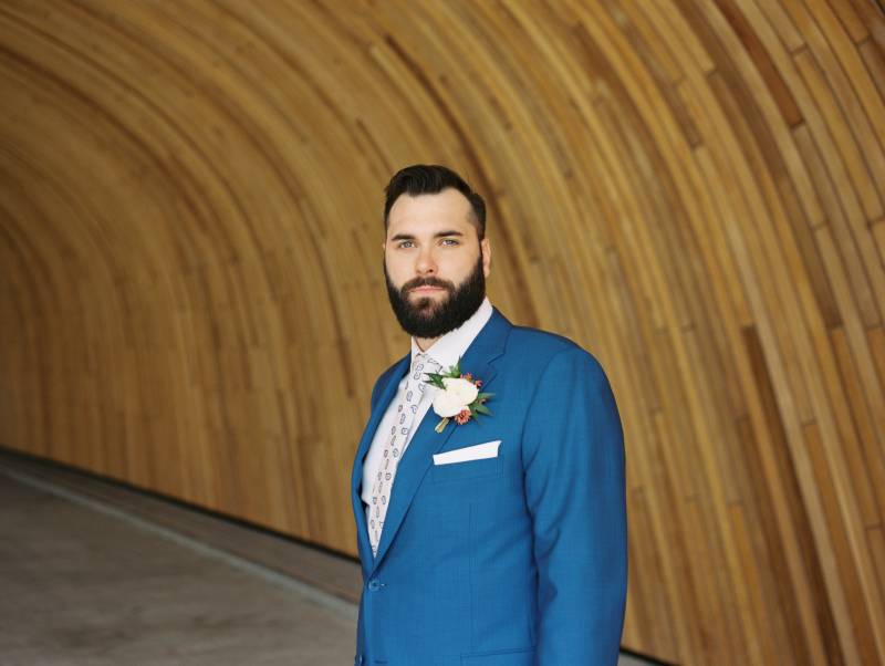 Groom in blue  suit and white boutonniere looks  into distance  