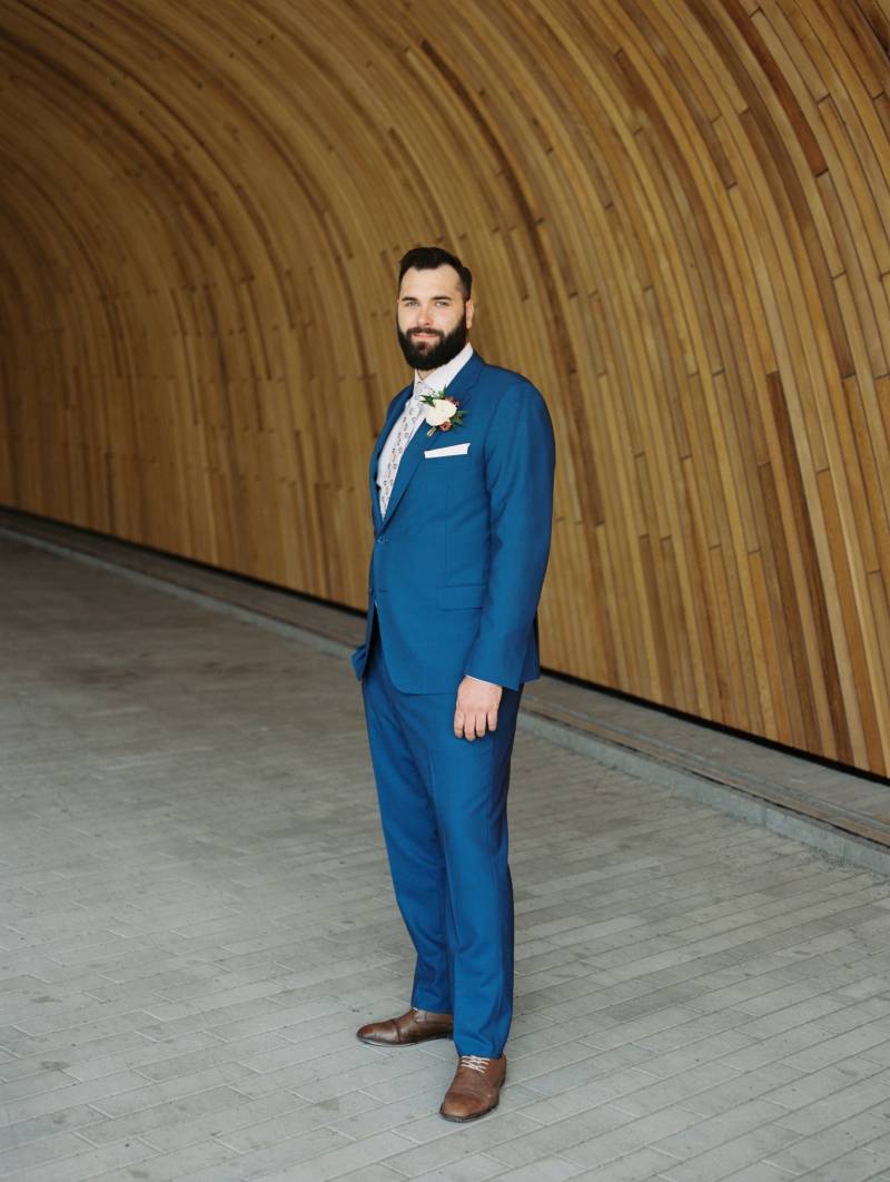 Groom in blue  suit and white boutonniere looks  into distance  