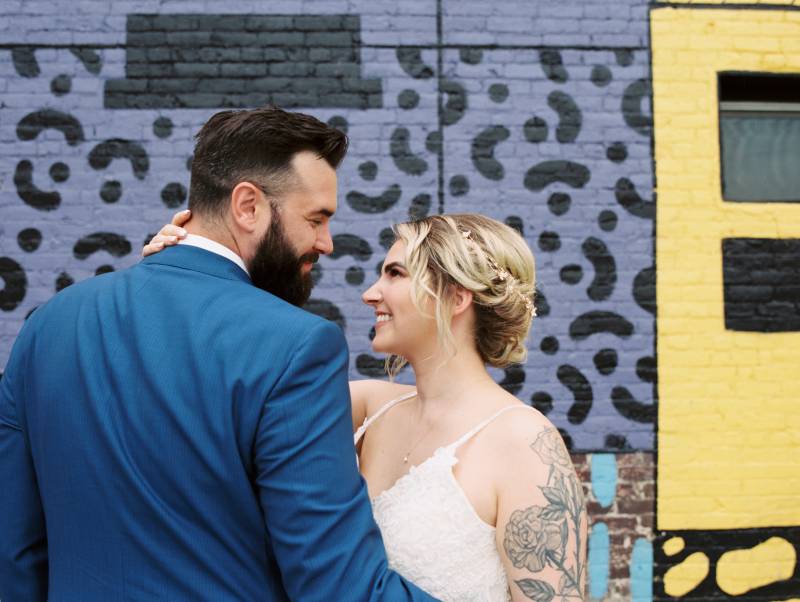 Bride and groom stare intensely against brick wall 