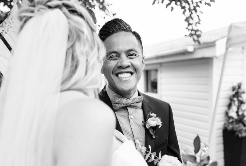 Groom grinning facing bride black and white