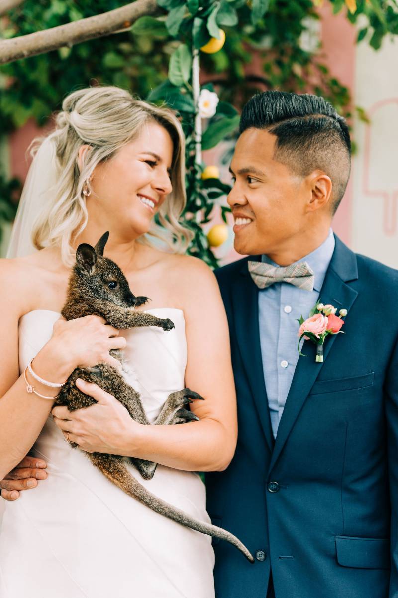 Bride holding kangaroo smiling at groom 