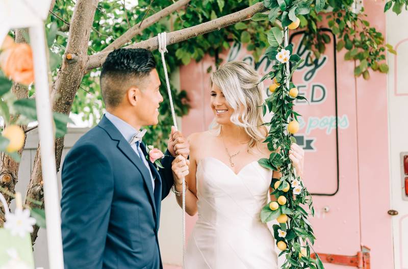 Bride and groom smiling holding rope swing rope with floral decoration 