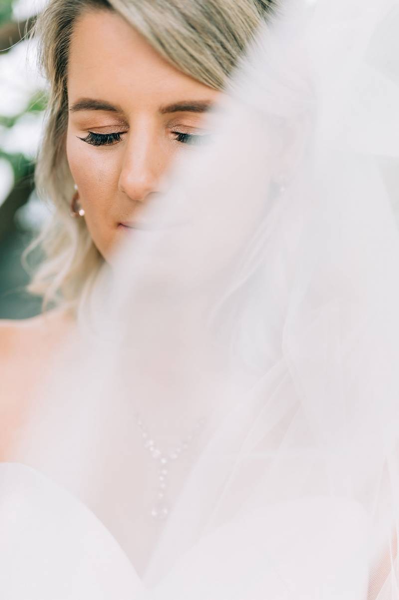 Bride with eyes closed behind white veil 