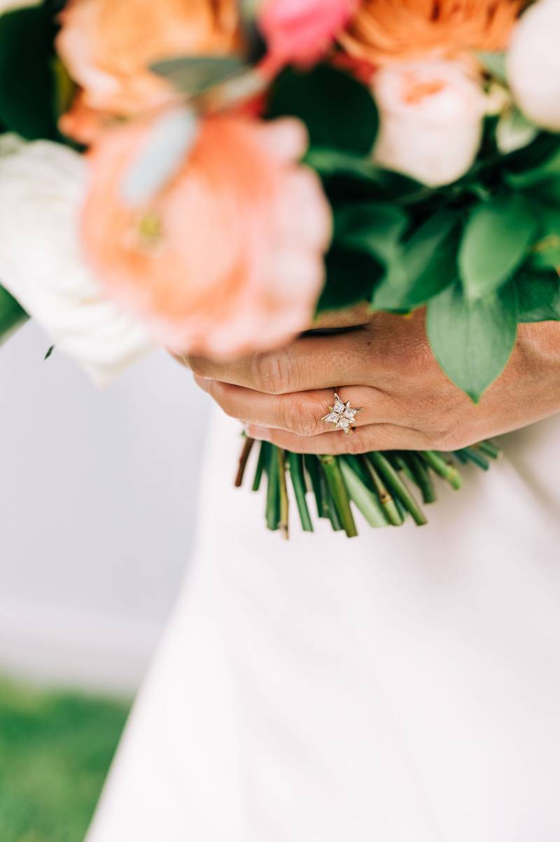 Hand with ring holding peach and white bouquet 