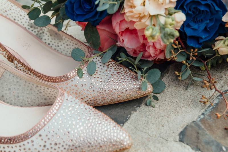 Pink gold studded heels beside blue pink and white flowers