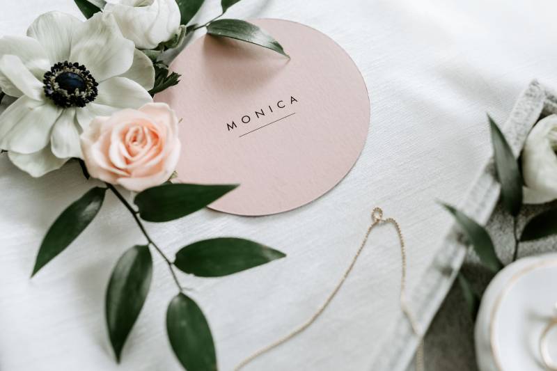 Blush and white floral accents around small gold chain on white table 