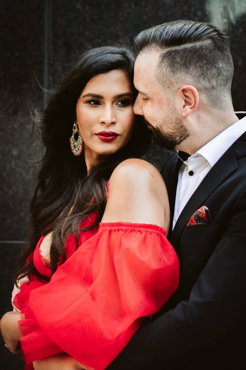 Groom embraces bride from behind looking over shoulder 