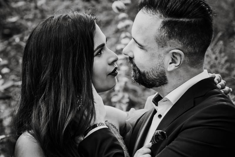 Groom touches cheek of bride looking intently 