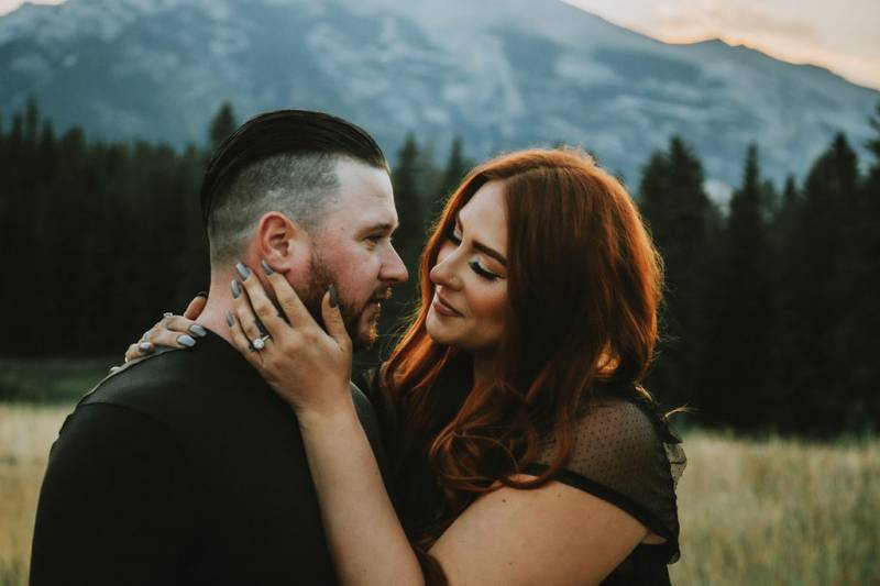Woman smiling touching mans face in front of mountains and forest 