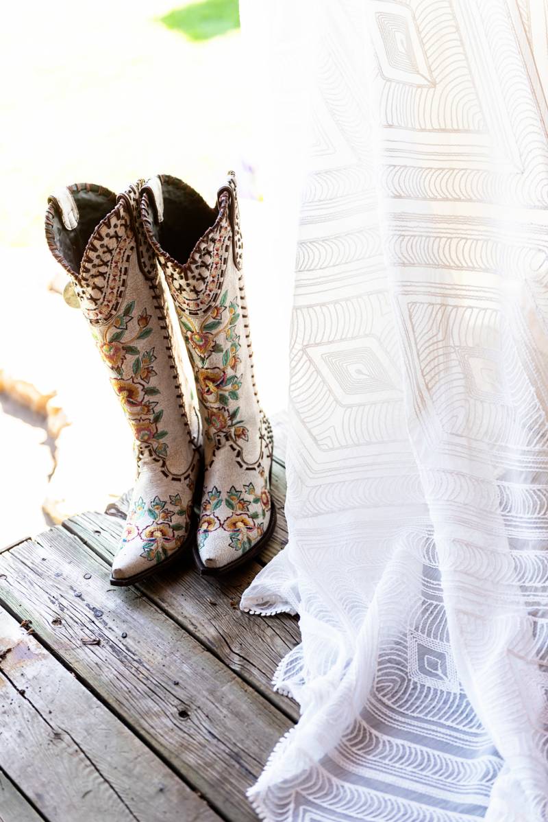 Floral embroidery on beige cowboy boots beside white dress 