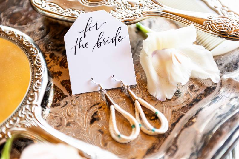 White note with white looped earrings on gold table 