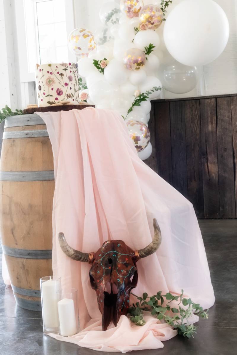 Bull skull on the ground on blush fabric over brown barrel 