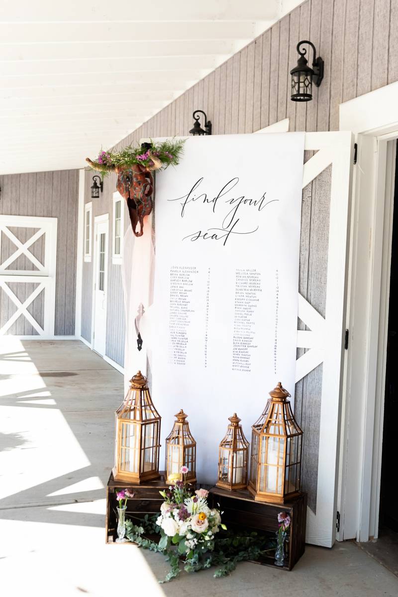 Large white sign with gold lanterns in front outside beige barn