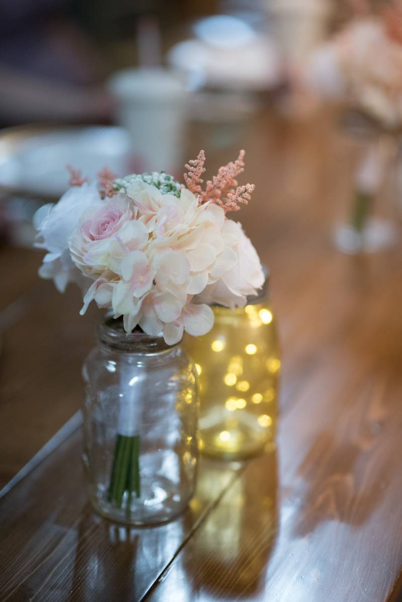 White and pink flowers in mason jar on wood table 