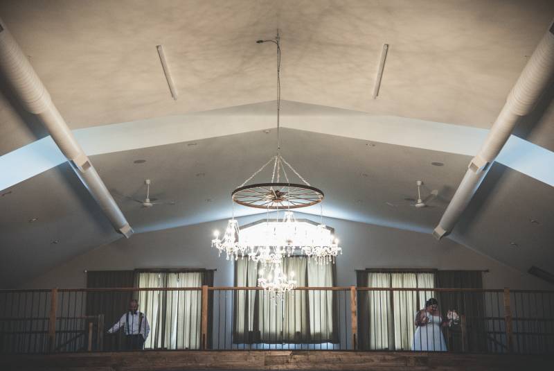 Large chandelier hanging under arched roof in front of balcony 