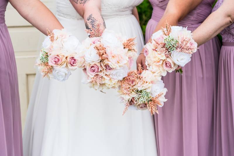 Bridesmaids hold out blush pink and white bouquets 