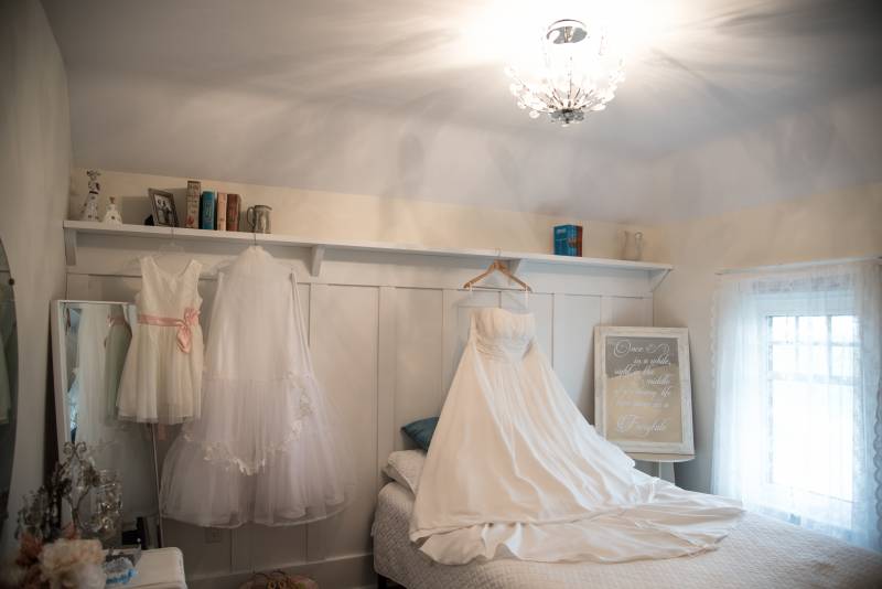 Three White wedding dresses hanging on ledge above wed 