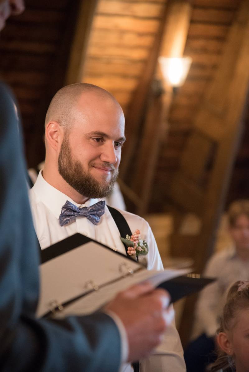 Groom stands smiling while officiant holds vows