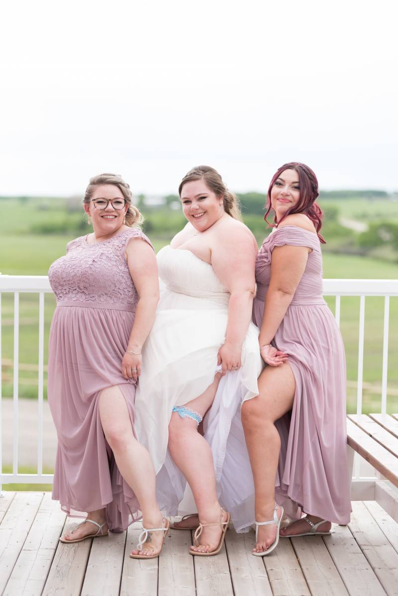 Bridesmaids stand in line lifting skirt to show pointed leg