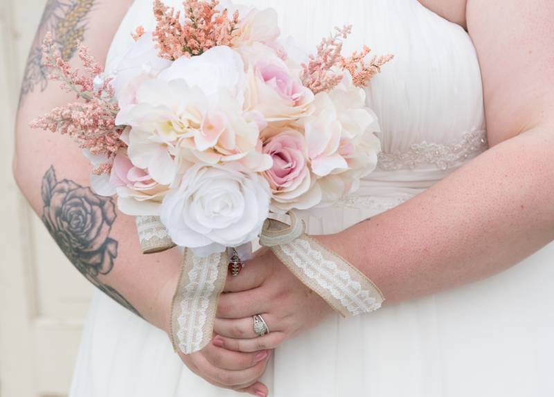 Bride holding white and blush pink bouquet with white ribbon 