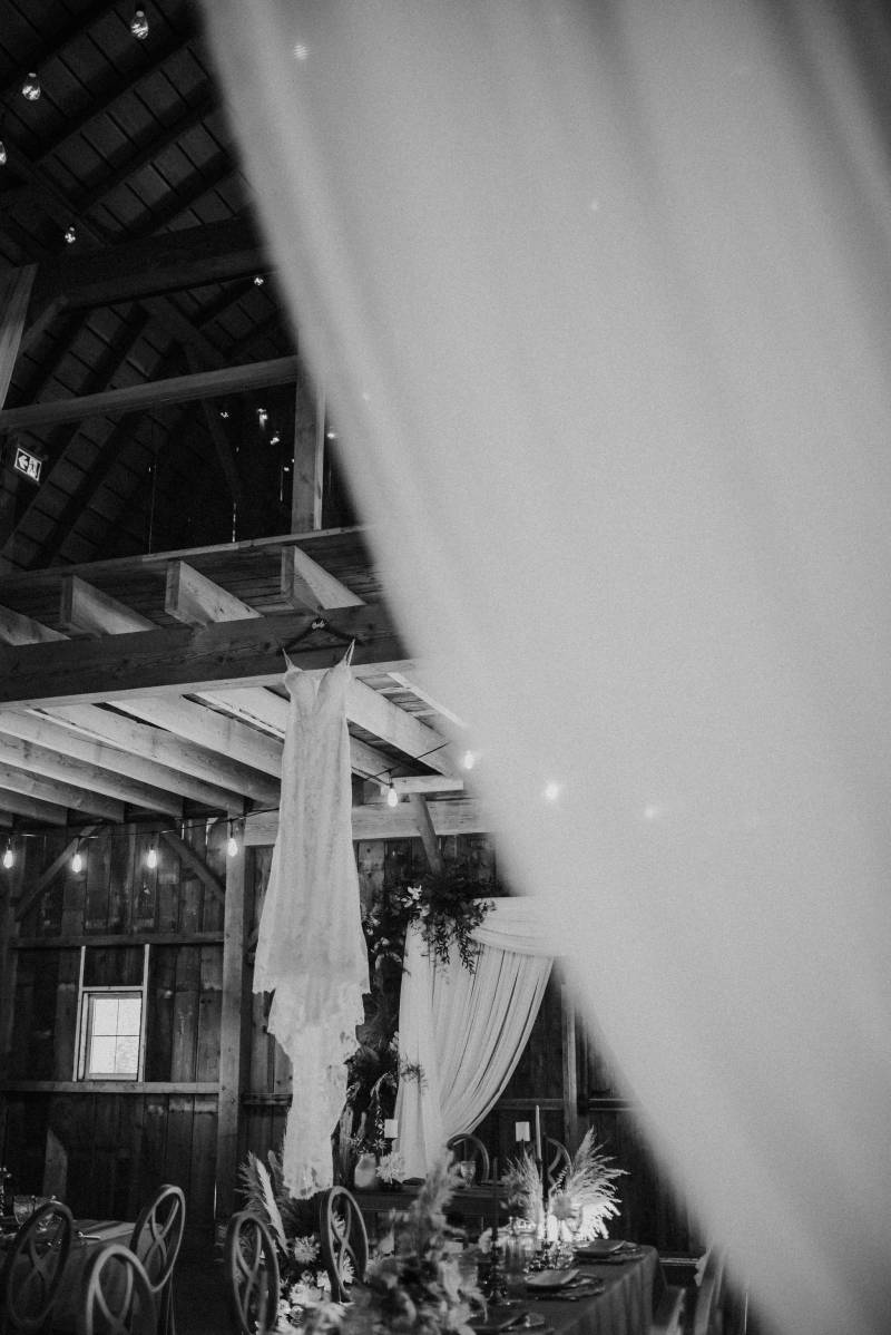 White dress hangs from balcony in front of macramé wedding arch 