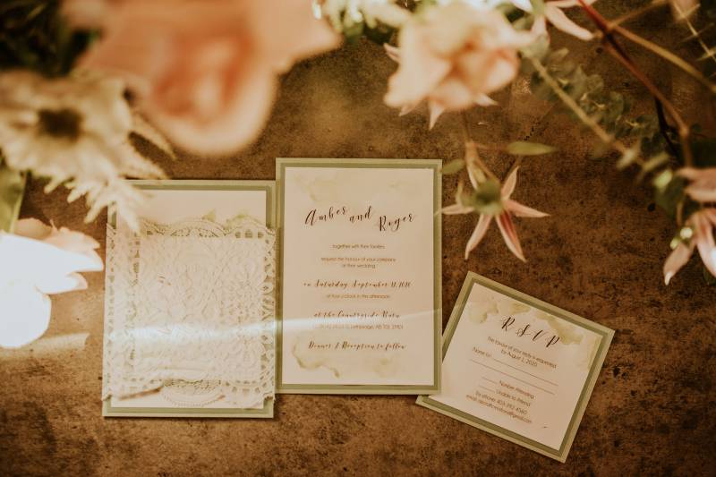 Wedding invitation flat lay with gold detailing under blush flowers 