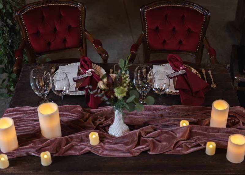 Table with candles and floral centerpiece table scape with burgundy napkins and seats 