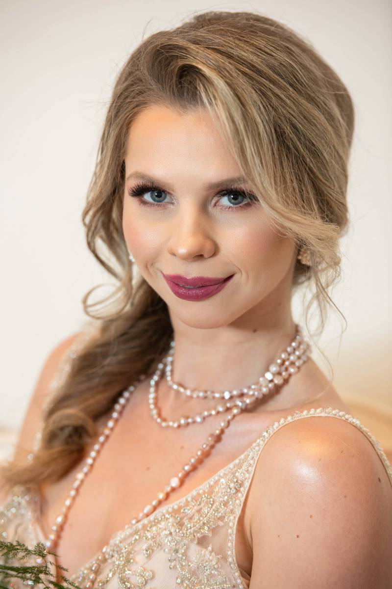 Bride smiling in beige dress with pearl necklace 